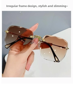 Close-up of rimless gradient brown sunglasses with irregular wavy edge cutting and gold frames
