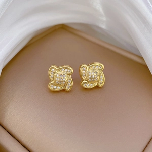 Detail of gold clover earrings with micro-pave white zircons on champagne velvet