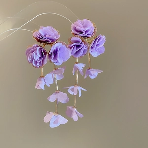 Detail view of purple chiffon flower earrings with silk tassels and golden metal accents