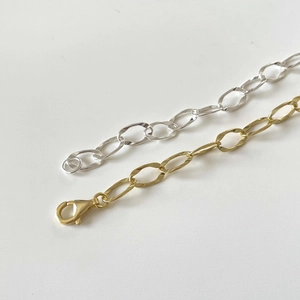 Detail of silver and gold link chain bracelets featuring smooth oval loops and lobster clasp