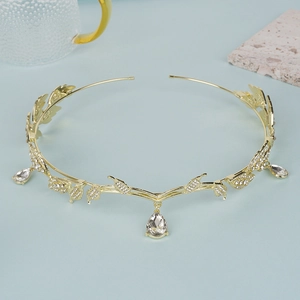 Elegant gold leaf crown with sparkling rhinestones and teardrop pendants on blue background