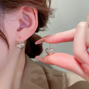 Detail of silver heart-shaped earrings featuring a stylish 3D wrinkled metal texture