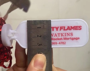 Detailopname van 2,5 cm breedte van een witte plastic tag met rode metalen franje decoratie