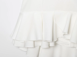 Close-up of elegant white layered ruffles and fine woven fabric texture on mini dress