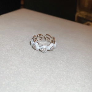 Detailed macro view of silver-tone open ring with white enamel and heart zirconia