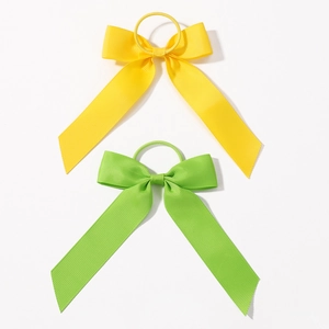 Détail de chouchous nœuds en ruban gros-grain jaune et vert avec longs pans sur blanc