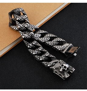 Detail of vintage silver skull charm on punk titanium steel link bracelet for men