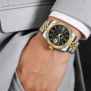 Close-up of luxury men's steel calendar watch with golden bezel on a grey suit wrist
