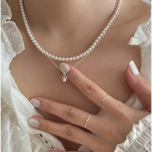 Close-up of double layer pearl and silver bow necklace on model neck with lace