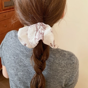 Detail view of a vintage beige and brown floral scrunchie on a braided hairstyle