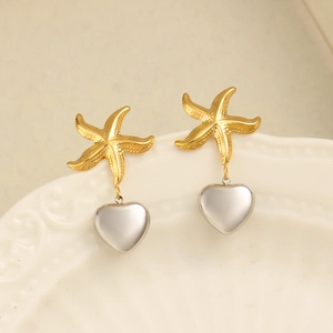 Elegant gold starfish and silver heart drop earrings on a white textured display tray