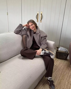 Détail d'une veste marron texturée portée avec un pantalon large et des baskets vintage