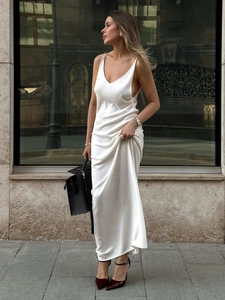 Detail of white knitted long slip dress with V-neckline and elegant flowing texture