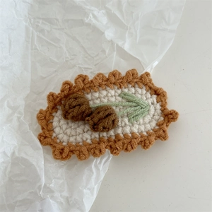 Detail of handmade crochet hair clip with 3D cherry fruit design and woven scalloped edges