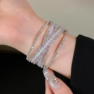 Detailopname van meerlaagse kruisarmband met fonkelende strass steentjes en parels