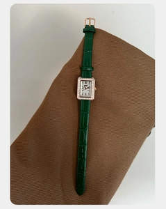 Dettaglio dell'orologio rettangolare oro rosa con cristalli e cinturino verde