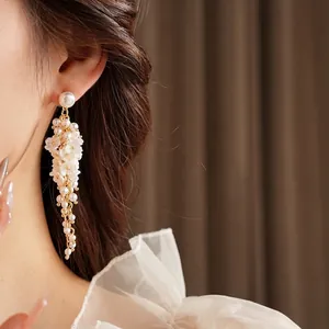 Floral resin earrings with pearl tassels and gold metal frame shown on a model