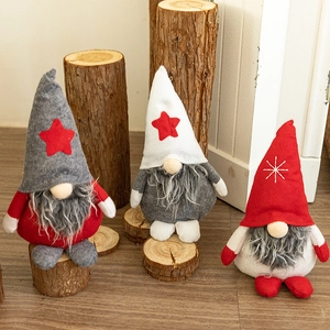 Three plush Christmas gnomes with felt hats and fiber beards on rustic wooden logs