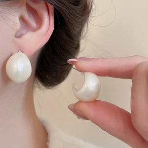 Close-up of iridescent drop earrings on ear showing pearlescent finish and modern design