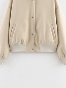 Close-up of beige tweed jacket showing metal buttons and ribbed hem detail