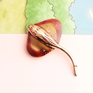 Detailed macro view of golden stingray brooch with textured reddish-brown enamel finish