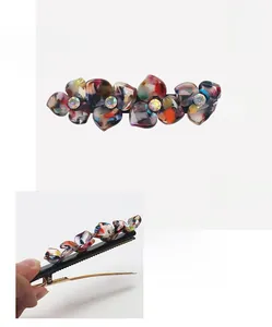Detail showing 9.2cm floral acetate hair clip with iridescent petals and inlaid rhinestones
