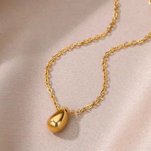Macro view of polished 18k gold plated teardrop pendant on minimalist stainless steel chain