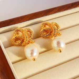 Elegant gold twist knot earrings featuring baroque pearls in a beige velvet jewelry box