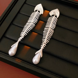 Macro shot of silver fishbone earrings with white pearls on a black leather jewelry box