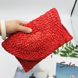 Detail of red handmade woven corn husk clutch bag with intricate fan-shaped straw patterns