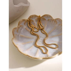 Detailed macro view of 18k gold stainless steel tassel earrings in a floral tray