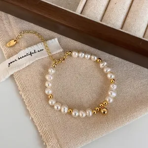 Détail d'un bracelet en perles d'eau douce avec perles dorées et pendentif sphérique