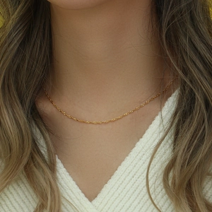 Dettaglio di una collana a catena a onde d'acqua placcata in oro 18K indossata da una modella
