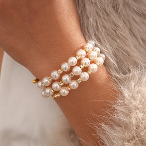 Close-up of layered pearl bracelet with gold accents and rhinestones on woman's wrist