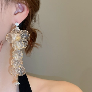Detail of long floral tassel earrings with acrylic petals and gold accents on model