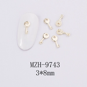 Détail des breloques à ongles en alliage doré de 3x8mm sur un tissu blanc texturé