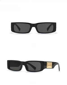 Detail of black rectangular sunglasses with golden metal accents on the temples