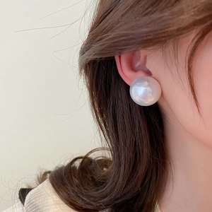 Close-up of a large round faux pearl earring with aurora luster on a female model