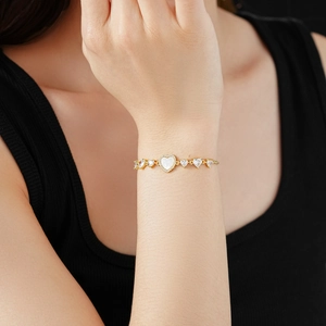 Detail of adjustable gold plated heart bracelet with zircon and mother of pearl on wrist
