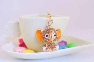 Detailed macro view of crystal elephant keychain with orange enamel ears and gold finish