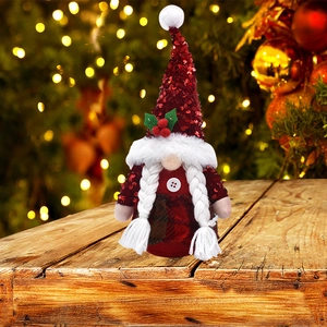 Détail du chapeau à paillettes rouges du gnome avec houx sur une table en bois