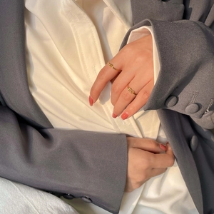 Close-up of minimalist gold twisted knot rings worn by a model in elegant attire