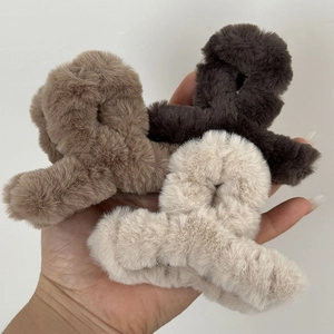 Detailed view of three plush faux fur hair claws in beige, tan, and dark brown colors