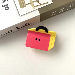 Detail of pink and yellow acetate bear clips in handbag shape on an open book background