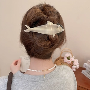 Detailed back view of a beige dolphin-shaped hair claw clip with rhinestones in use
