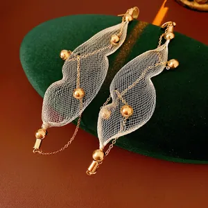 Elegante goldene Tropfenohrringe aus Metallnetz mit weißen Perlen auf grünem Samt