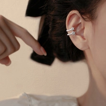 Detail view of a silver star ear cuff with sparkling zircons on a woman's ear