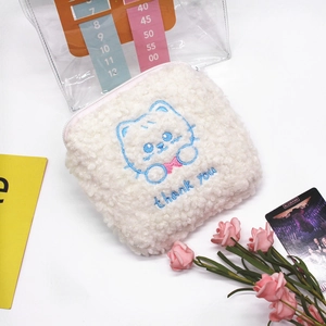Detail of white plush sanitary pad pouch featuring a blue embroidered cat and zipper closure