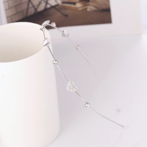Silver metal headband featuring pearl hearts and sparkling rhinestones on a ceramic cup