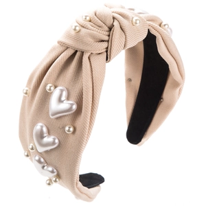 Détail d'un serre-tête noué beige avec tissu texturé et perles en forme de cœur doux